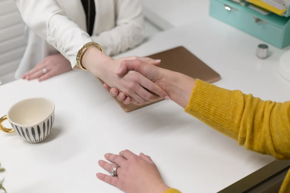 Two business professionals shaking hands at a desk